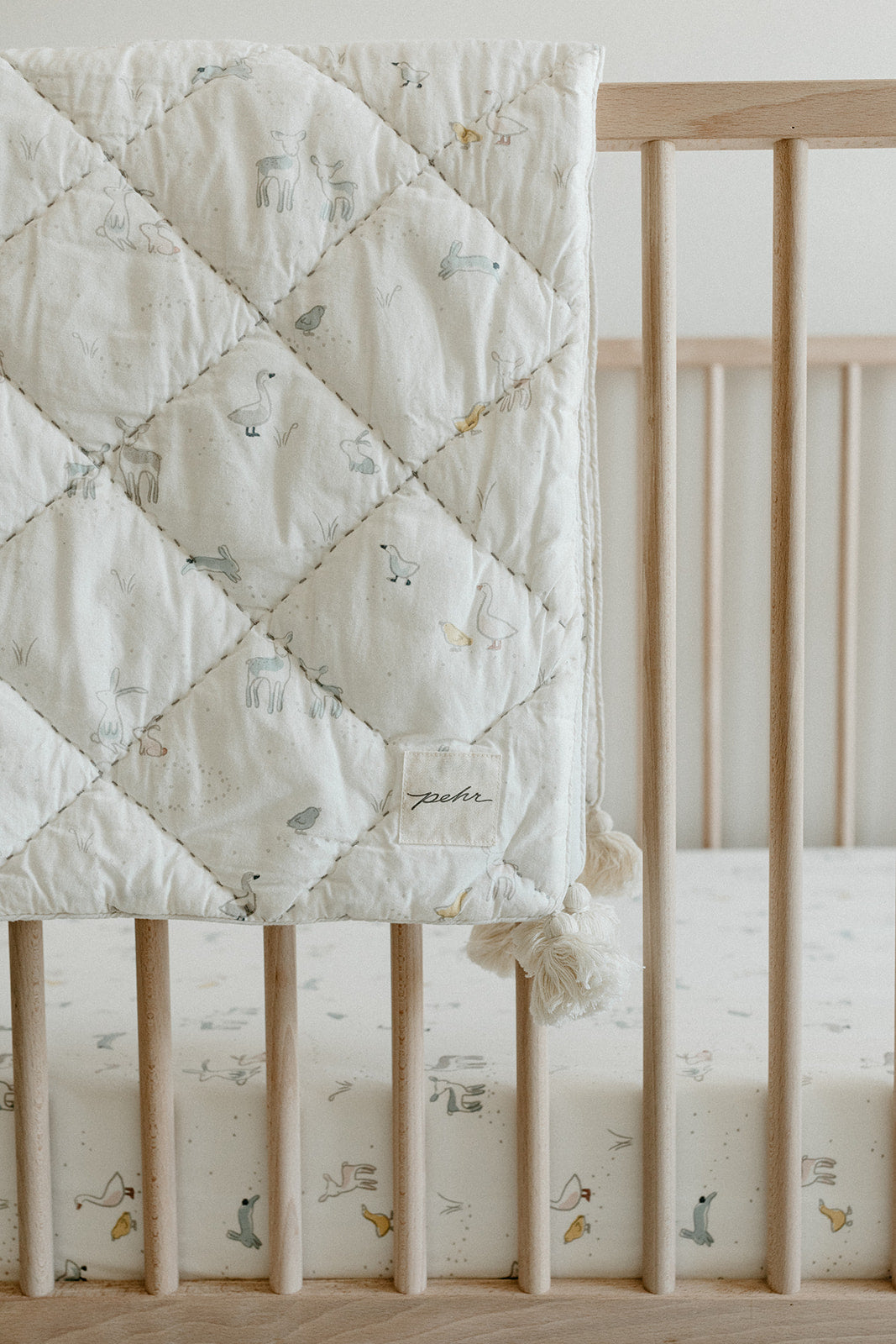 pehr just hatched blanket hanging on crib