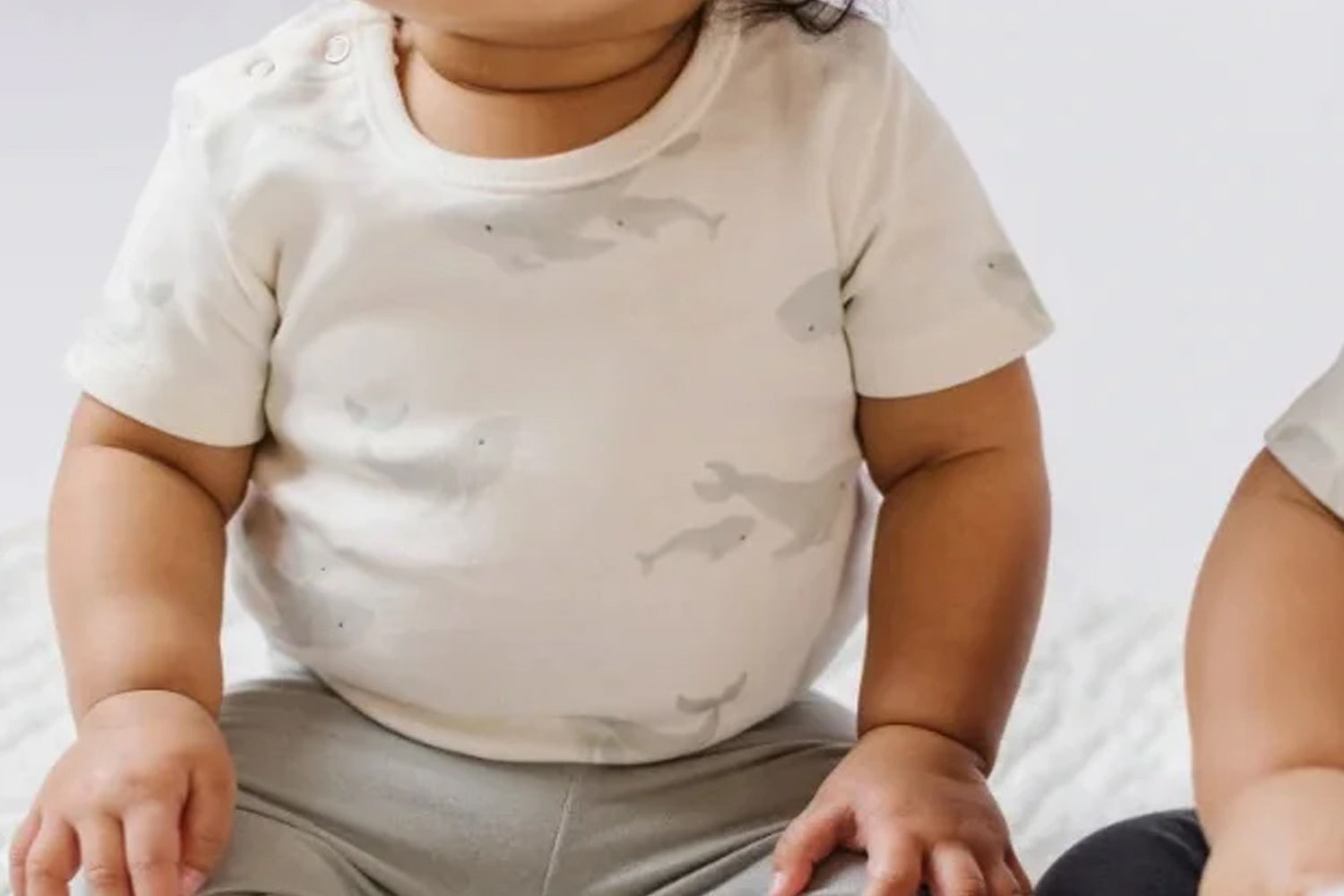 cute and chubby baby wearing one piece top with grey pants
