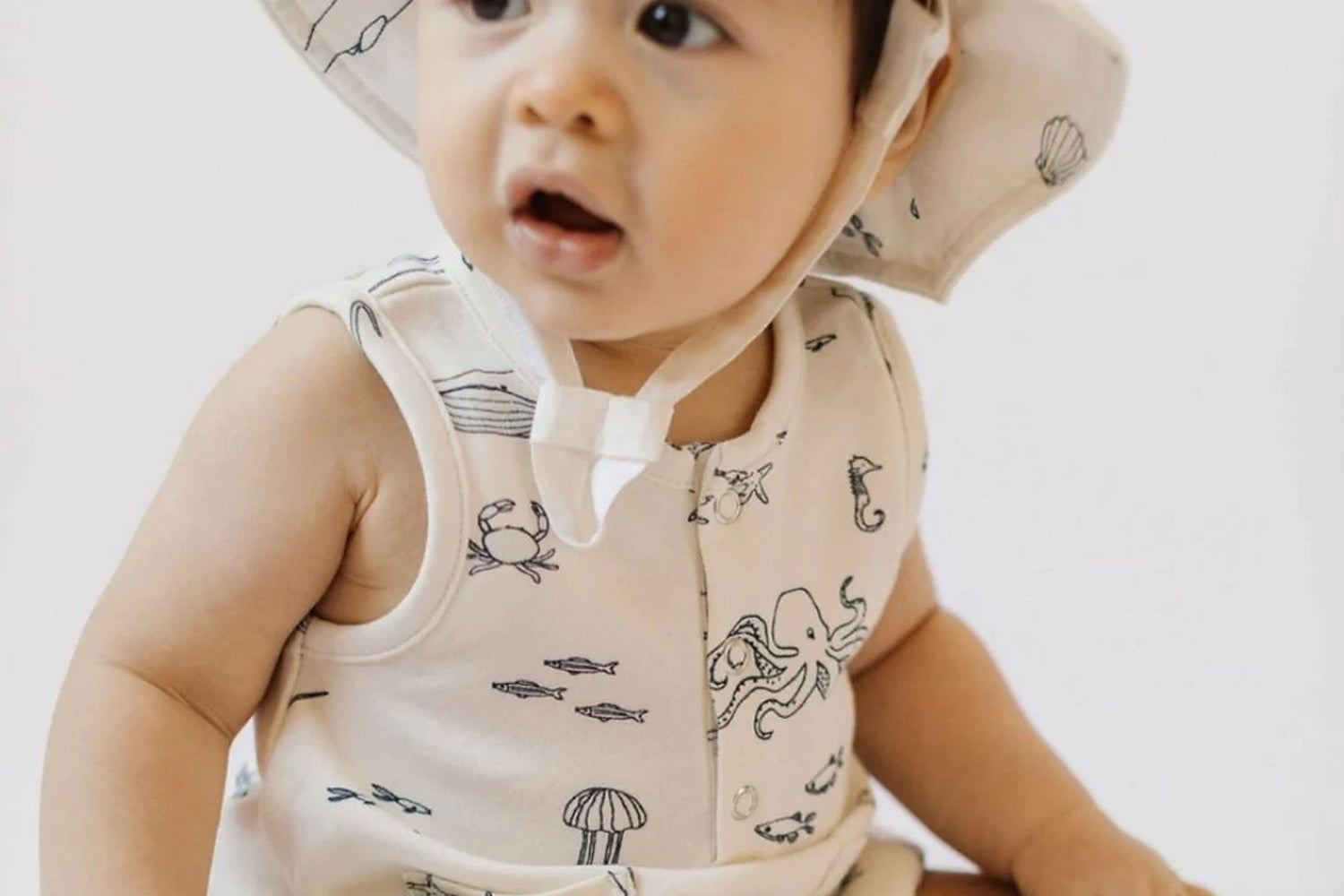 baby wearing pehr life aquatic apparel and looking surprised