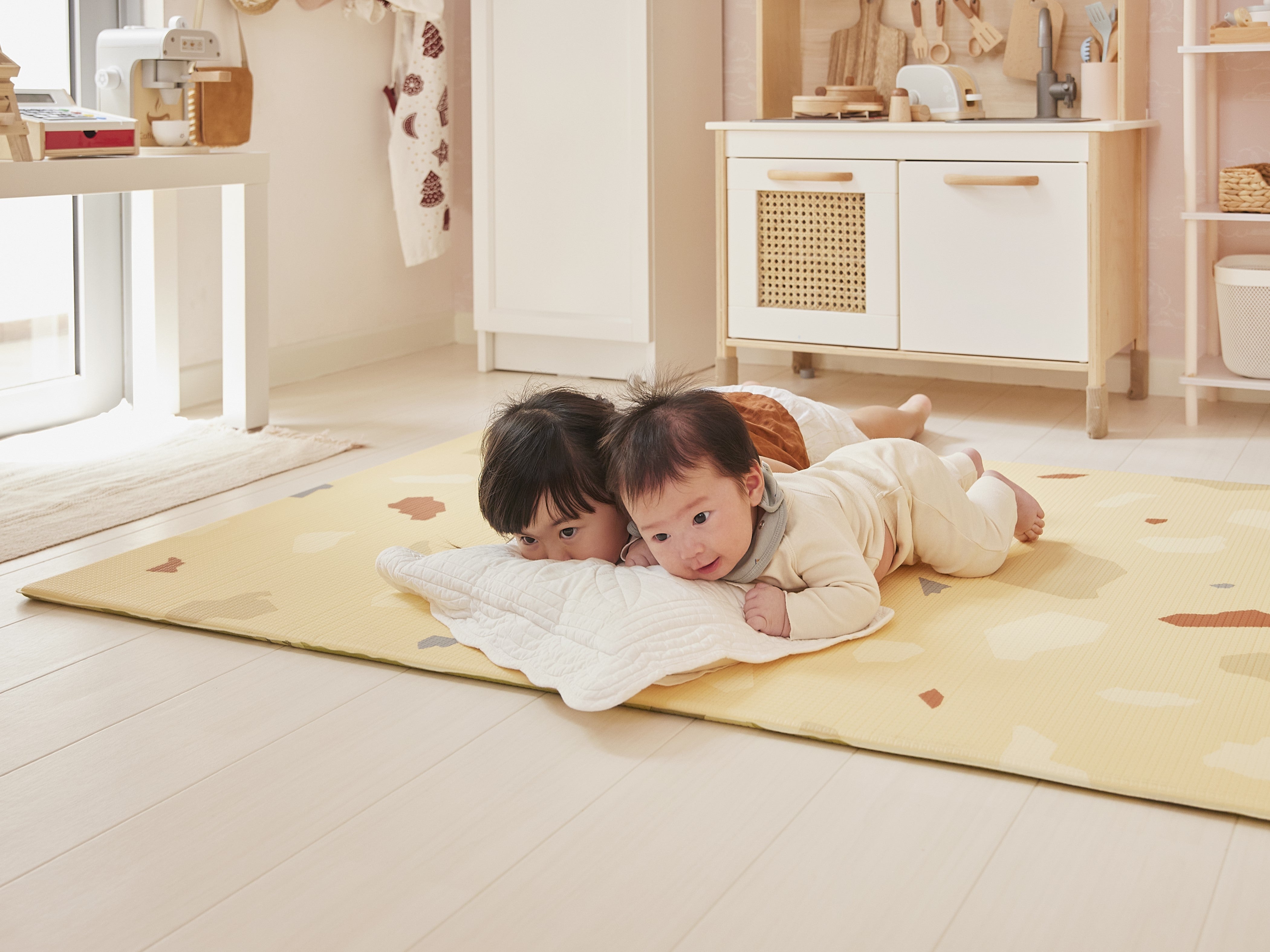 two babies lying on lollibly terrazzo play mat