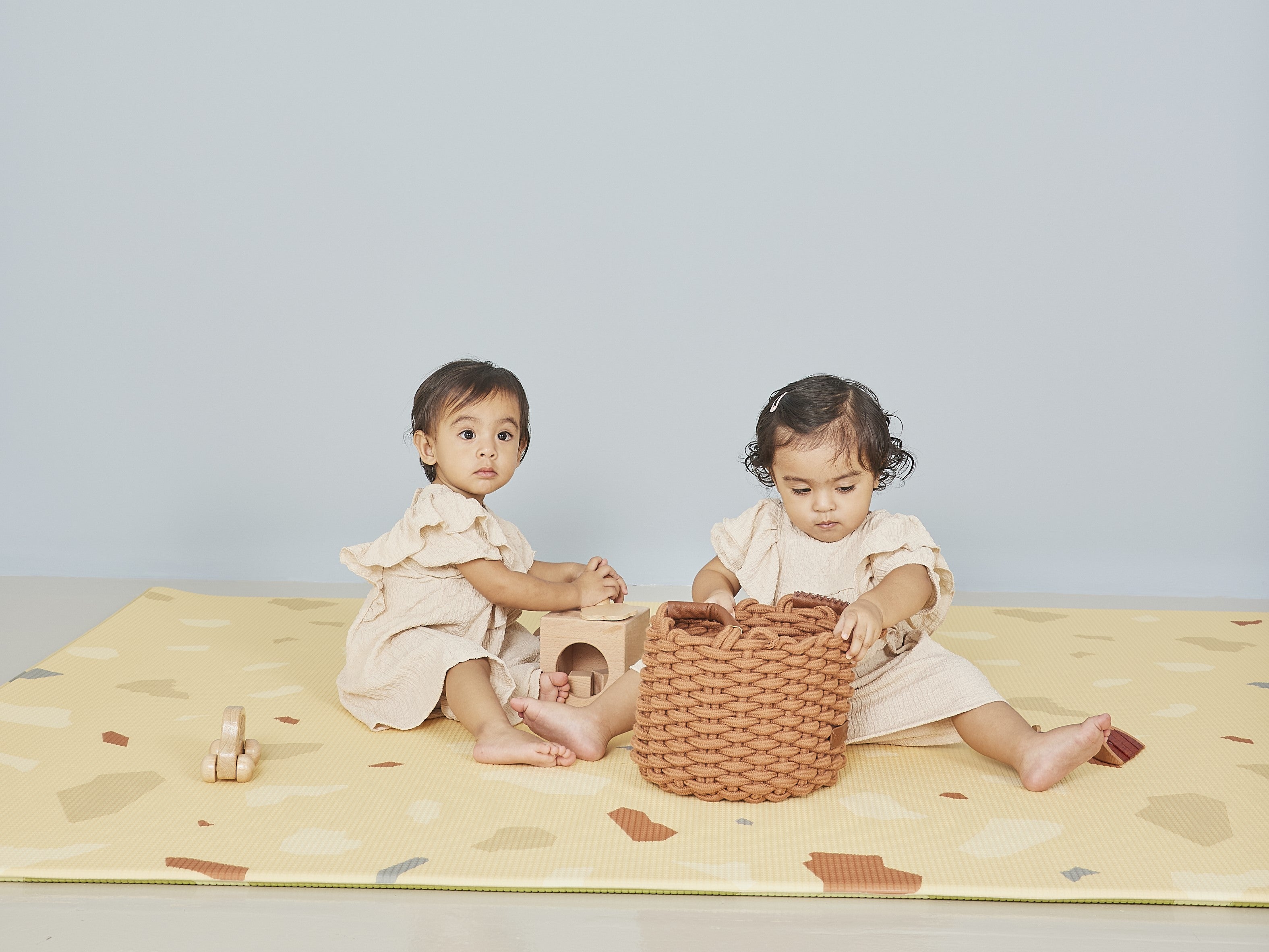 twin girls playing with toys on the lollibly terrazzo play mat