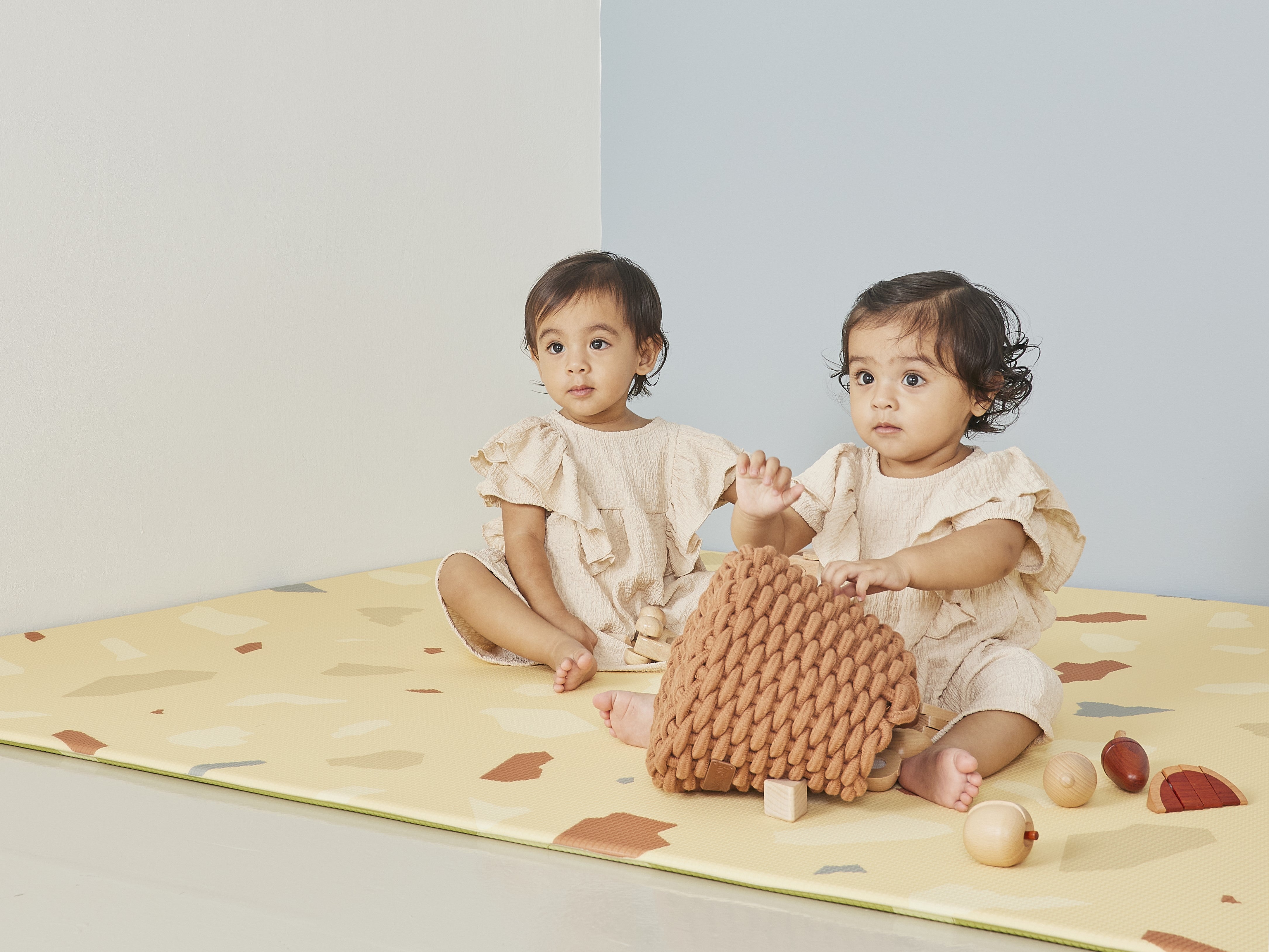 twins playing with wooden blocks on lollibly terrazzo play mat