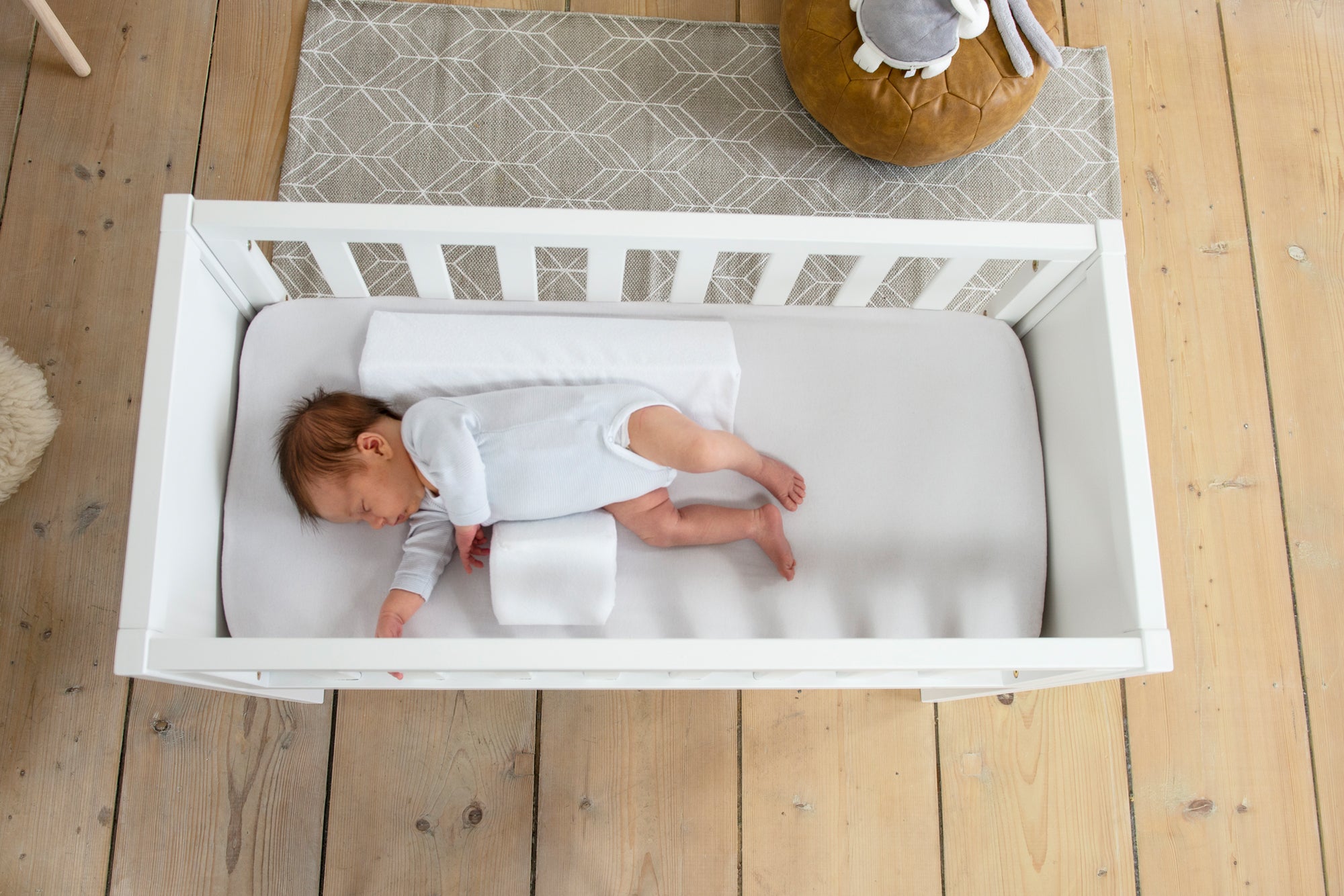 top down shot of baby sleeping with doomoo baby sleep positioner